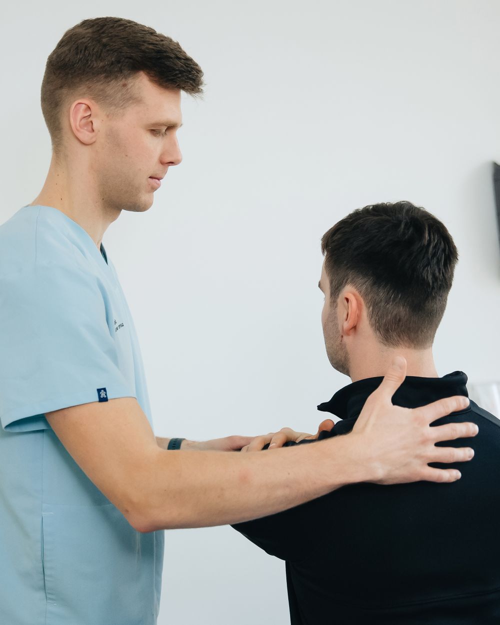 Owen assessing a patient's shoulder position in the clinic