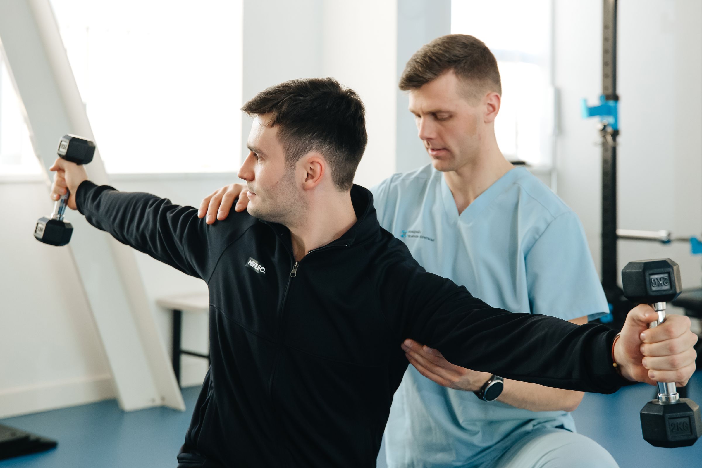 Owen supporting a patient's shoulder through a loaded side raise