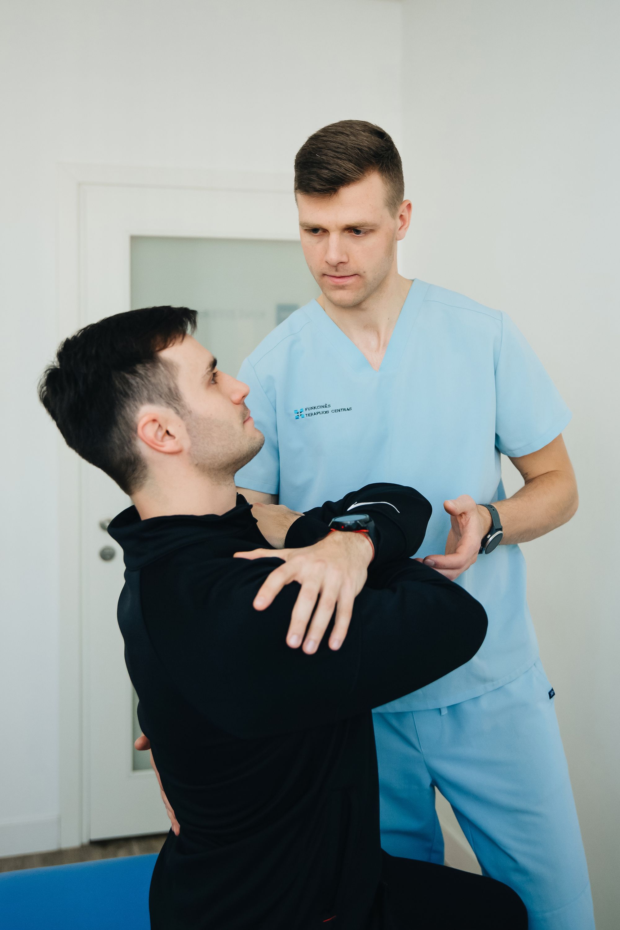 Owen measuring a patient's shoulder range across the body