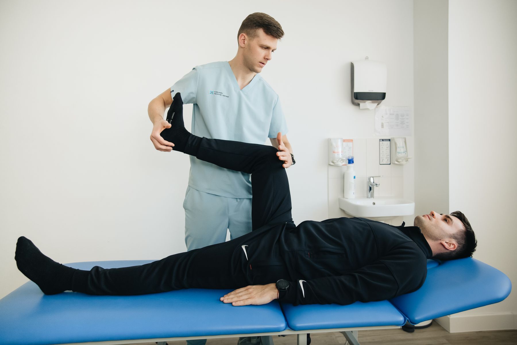 Owen raising a patient's straight leg on the treatment table to test hip flexion