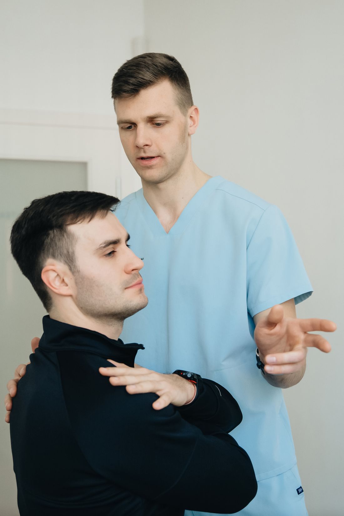 Owen Castellano guiding a patient's arm through a shoulder rotation
