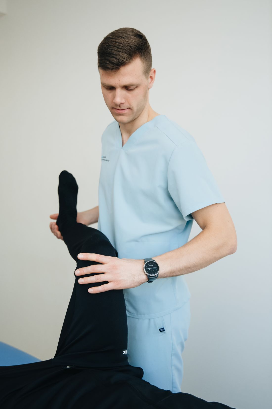 Owen holding a patient's knee in flexion during a strength and range check