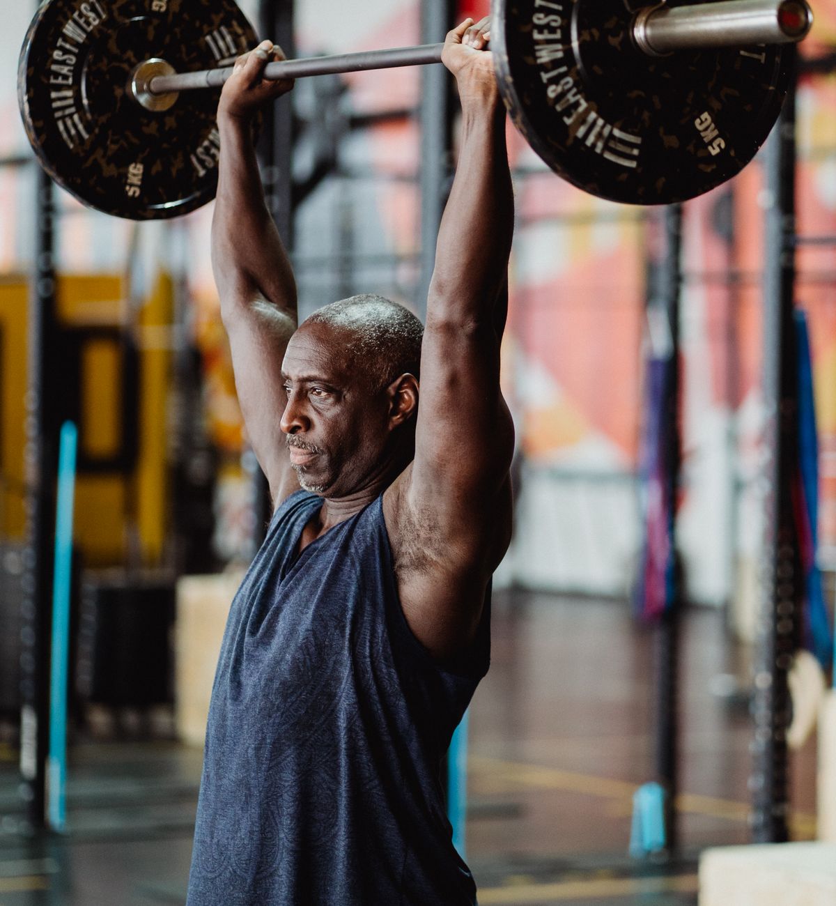 Man pressing a barbell overhead with both arms fully raised