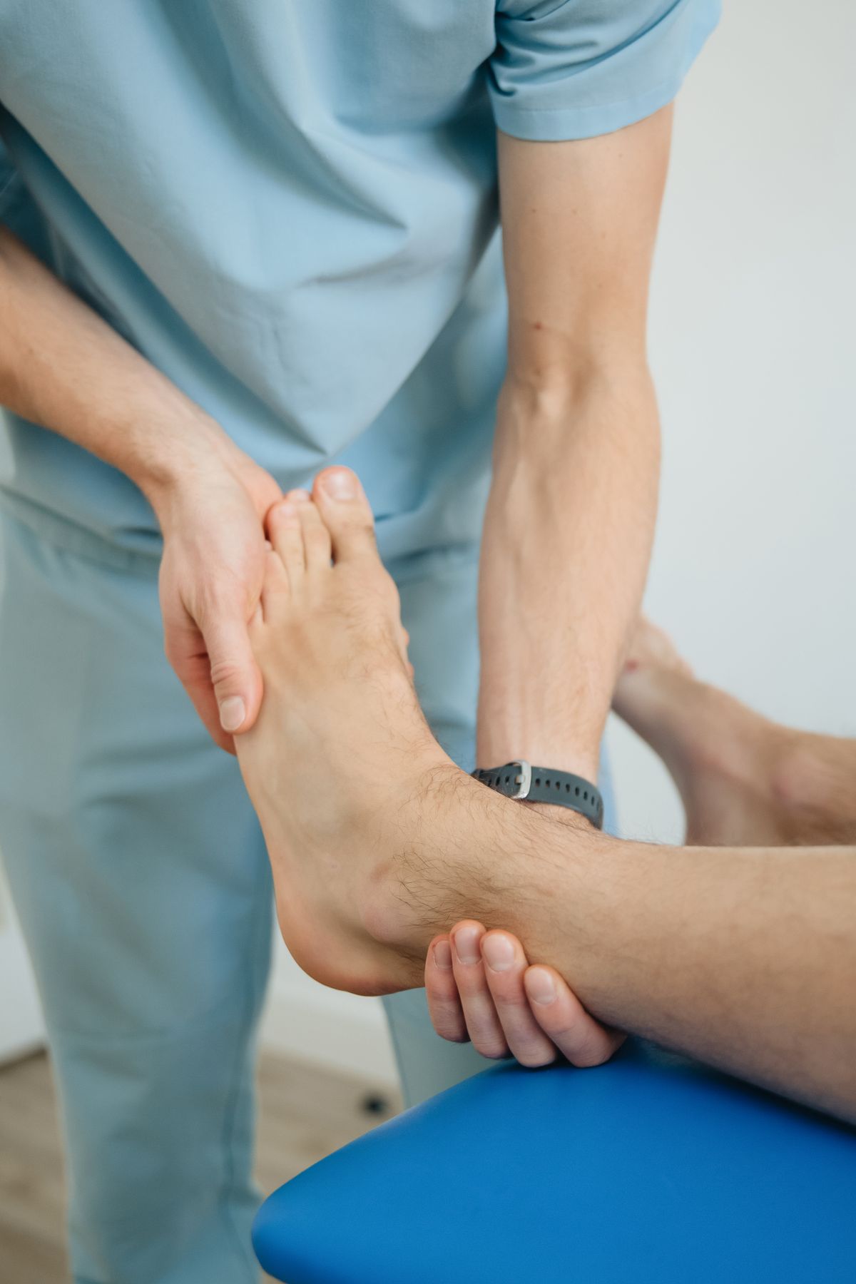 Close view of Owen's hands supporting a patient's ankle